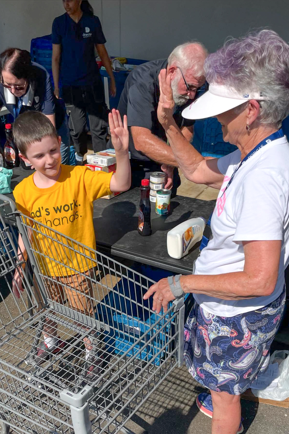A young boy and an older woman high-fiving.