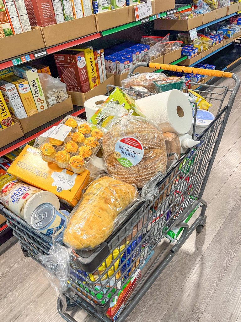 A shopping cart filled with food and paper towels from the NeighborUp pantry.