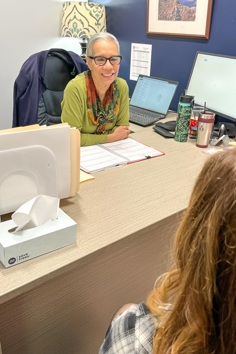 Evelyn at her desk smiling and helping someone in need.