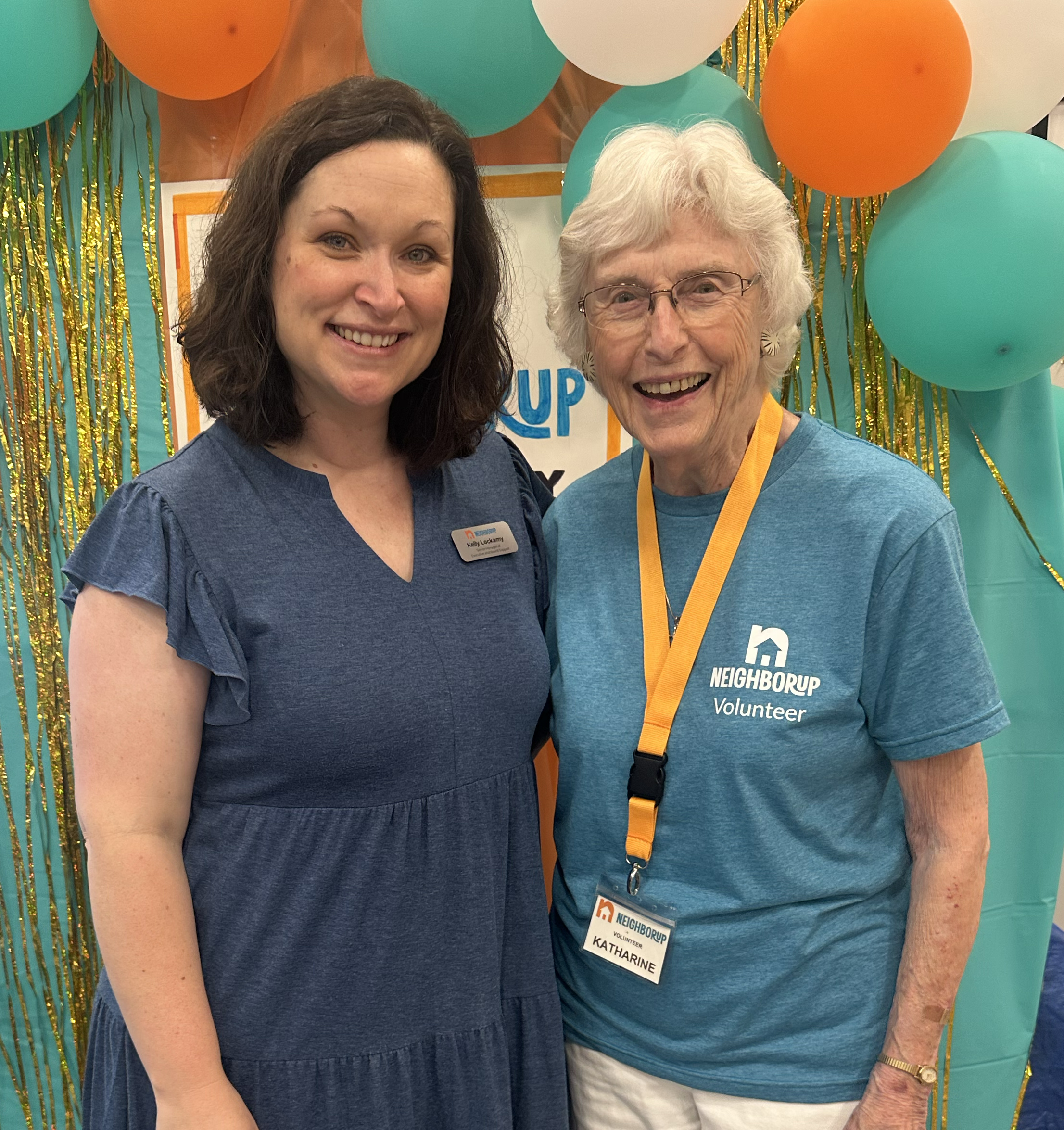Two women standing in front a balloon arch smiling